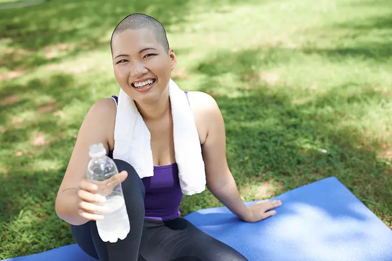 bald woman drinking bottle of water